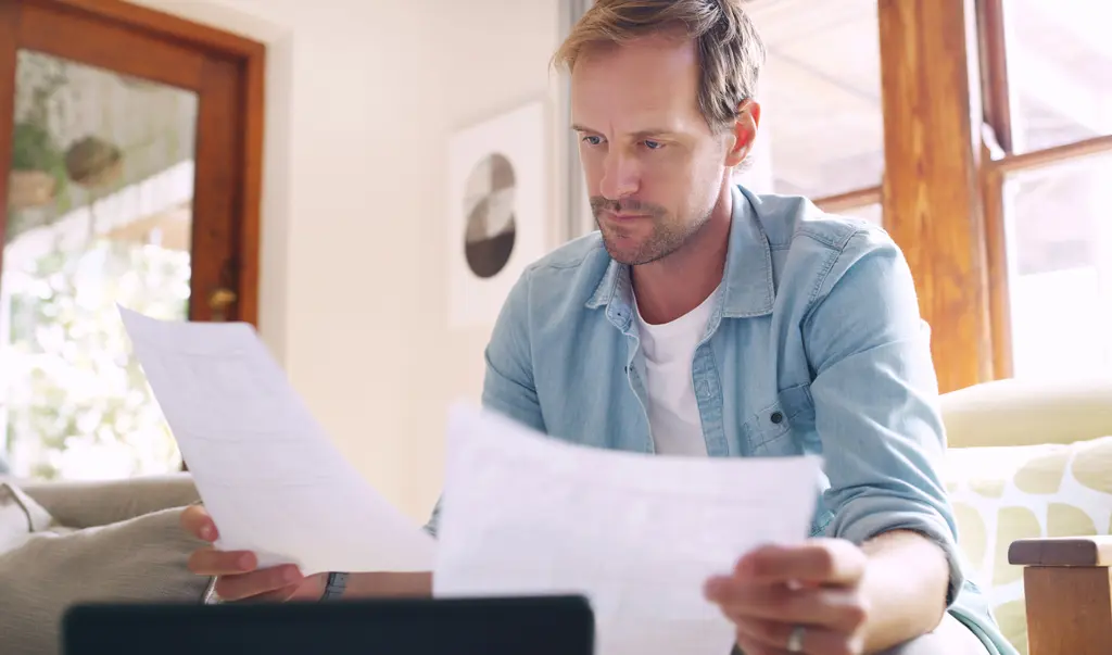 Homeowner reading a letter from an insurer next to a property insurance policy
